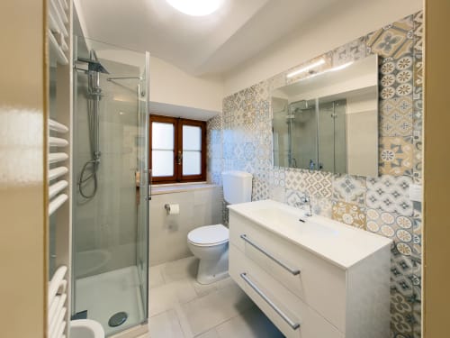 Modern bathroom in Serena apartment at Tuscan Sun Stays with patterned tile walls, walk-in shower, white vanity, and natural