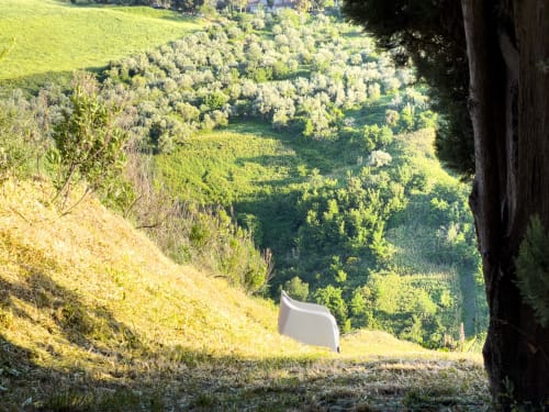White chair on hillside overlooking lush Tuscan valley with trees and green landscape at Tuscan Sun Stays, Lajatico