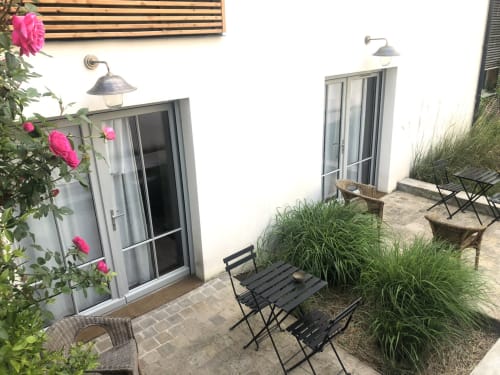 Patio privé du gîte Denis & Virginie à Versailles avec roses roses, chaises noires, herbes ornementales et vue sur la cour