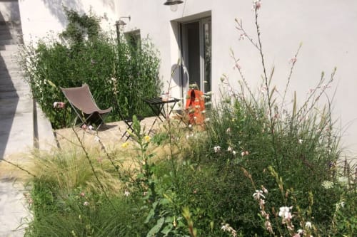 Terrasse privée du gîte Denis & Virginie à Versailles avec sièges, verdure luxuriante et plantes fleuries