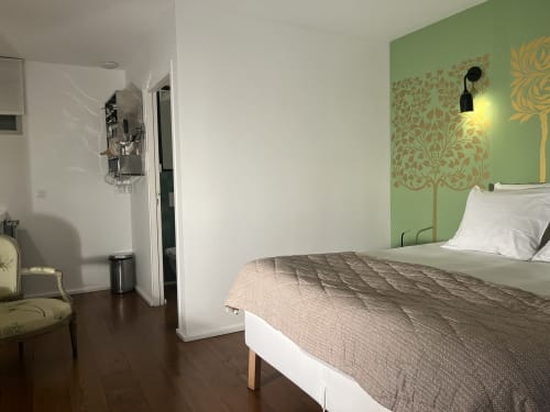 Chambre studio moderne à la Chambres d'hôtes de Versailles avec mur vert, fresque murale décorée, lit et kitchenette