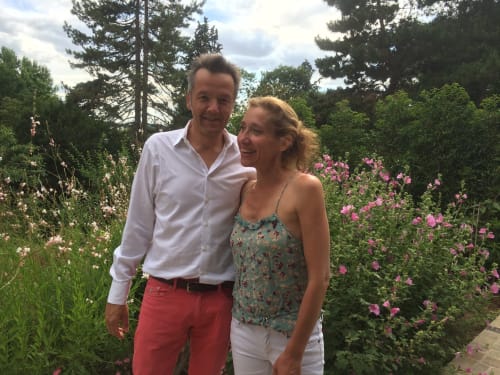 Couple souriant dans le jardin de roses en fleur de la maison d'hôtes Denis & Virginie, Versailles