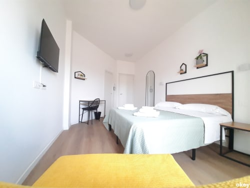 Camera moderna al B&B Bari Centro con letto matrimoniale, TV a schermo piatto, scrivania e arredamento minimalista a Bari