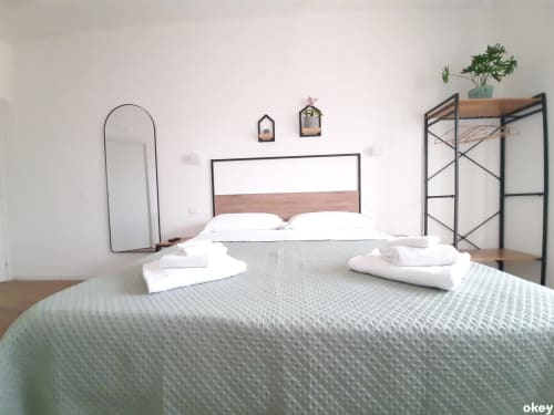 Camera moderna al B&B Bari Centro con letto matrimoniale, biancheria bianca, testiera in metallo, specchio rotondo e scaffale