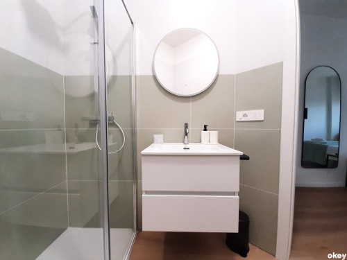 Bagno moderno con vanity bianca, specchio rotondo e cabina doccia in vetro presso il B&B Bari Centro a Bari