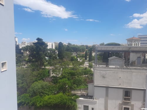 Vista di Bari dal balcone della camera d'albergo con parco verde, edifici e cielo azzurro
