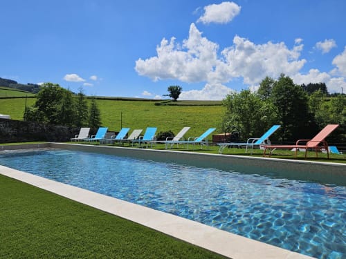 Piscine rectangulaire avec transats bleus surplombant les champs verdoyants de la location Gites Les Muriers à Bourgvilain