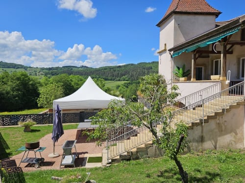 Gîtes Les Muriers : jardin cottage avec terrasse, chapiteau blanc et vue sur la campagne verdoyante de Bourgvilain
