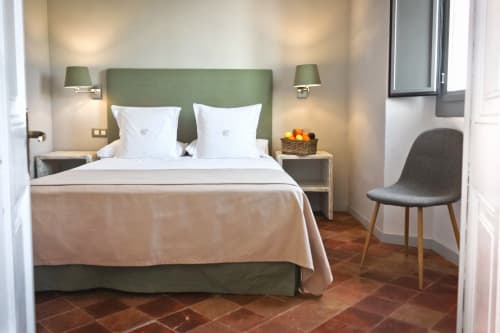 Suite lumineuse à l'Hôtel Casa Calella avec tête de lit verte, literie blanche, lampes jumelles et sol en terre cuite à Calella de