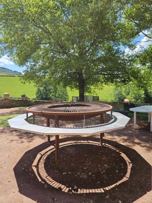 Espaces de détente circulaires avec bancs blancs dans le jardin des Gîtes Les Muriers, Bourgvilain, entourés de champs verdoyants