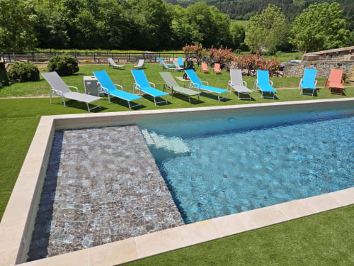 Piscine rectangulaire avec bains de soleil bleus sur pelouse soignée aux Gîtes Les Muriers à Bourgvilain, France
