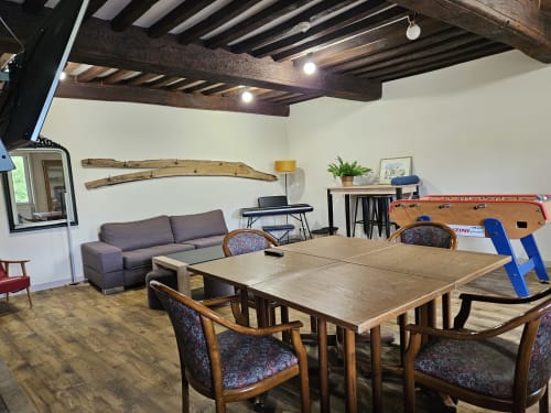 Salle à manger spacieuse du Gites Les Muriers avec table en bois, sièges confortables, baby-foot et équipements modernes