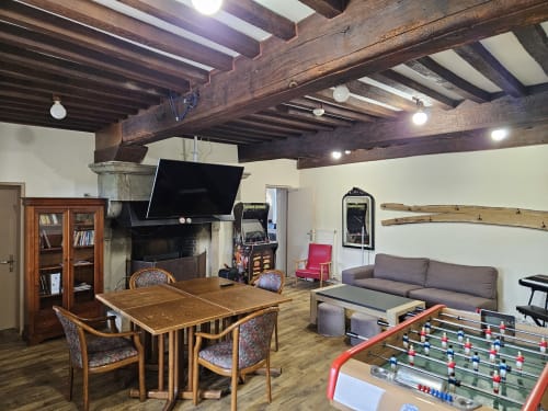 Spacieux séjour partagé aux Gites Les Muriers avec poutres apparentes, table à manger, baby-foot, TV et foyer