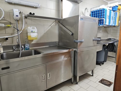 Cuisine aménagée du gîte Les Muriers avec évier inox, lave-vaisselle et étagères de rangement bleu