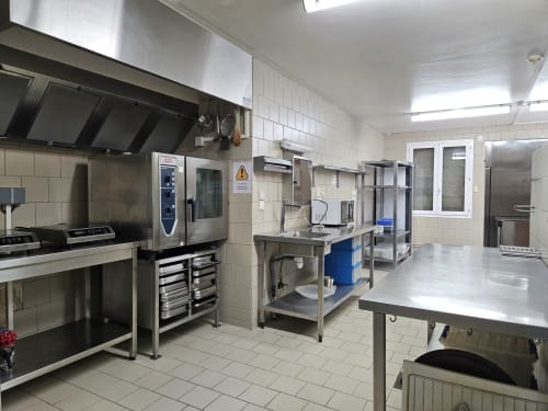 Cuisine professionnelle du gîte Les Muriers à Bourgvilain équipée d'appareils en acier inoxydable et de tables de préparation