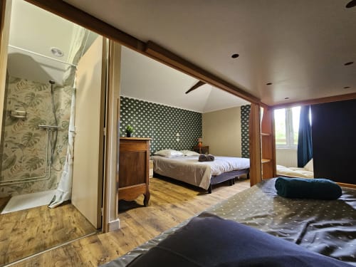 Suite spacieuse aux Gîtes Les Muriers avec salle de bain attenante, meubles en bois et décoration contemporaine à Bourgvilain