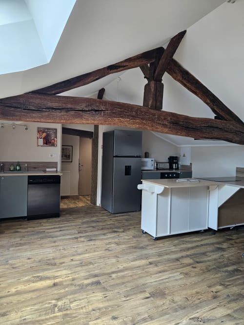 Cuisine moderne aux poutres apparentes, meubles blancs et électroménagers inox au Gîte Ornella