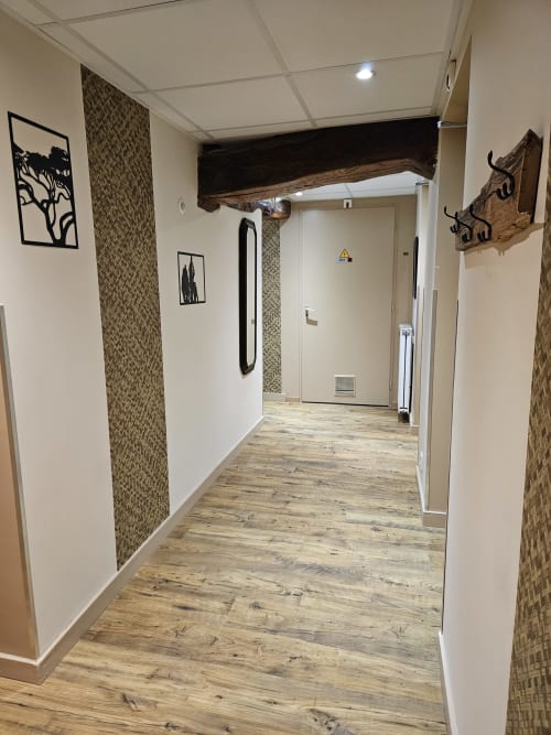 Couloir moderne du Gîte Ornella aux Gîtes Les Muriers avec parquet, panneaux muraux décoratifs et œuvres d'art rustiques
