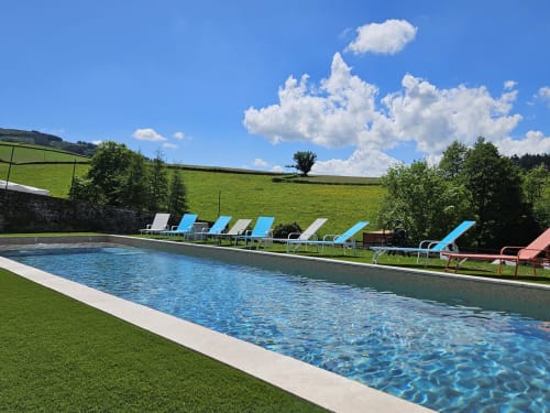 Piscine du resort avec transats bleus surplombant la campagne verdoyante aux Gites Les Muriers, Bourgvilain France