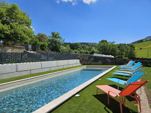 Piscine de luxe avec transats bleus aux Gîtes Les Muriers, Bourgvilain, entourée de jardins soignés et de collines ondulantes.