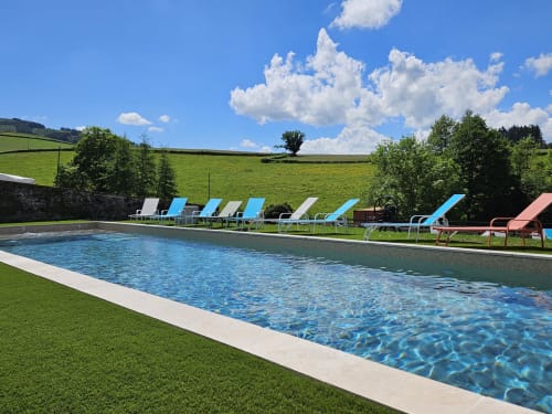 Piscine extérieure avec transats bleus aux Gîtes Les Muriers, Bourgvilain, entourée de jardins verdoyants et paysages vallonnés
