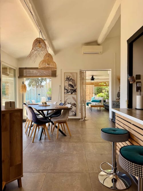 Salle à manger de villa moderne avec luminaires suspendus tressés, table ronde, vue sur mer et espace ouvert aux Villas d'A