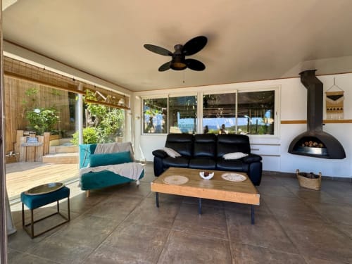 Villa moderne avec salon vue mer, canapé cuir noir, table bois, cheminée et accès terrasse