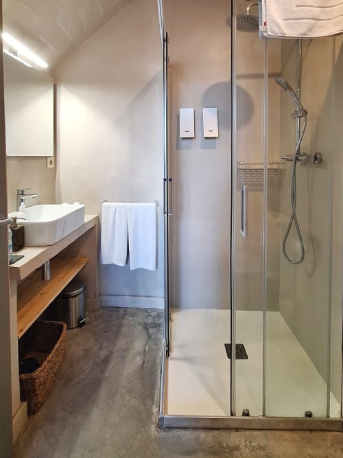 Salle de bain moderne de l'Hôtel Casa Calella avec douche à l'italienne, vasque et sol en béton à Calella de Palafrugell