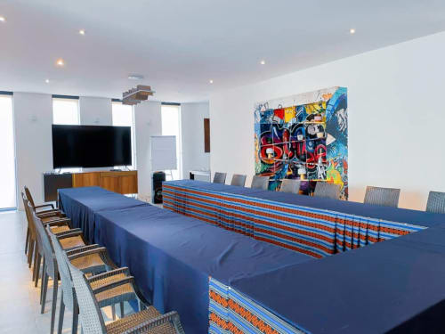 Modern conference room at Hôtel Du Parc in Somone with blue-draped tables, colorful artwork, and flat-screen TV