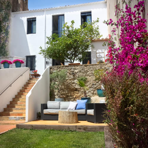 Patio de Casa Calella avec bougainvillées magenta, salon détente et architecture méditerranéenne à Calella de Palafrugell