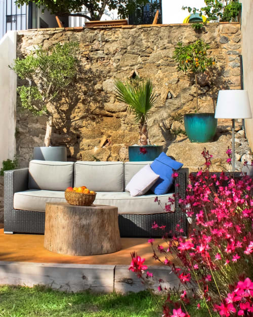 Terrasse côtière à l'Hôtel Casa Calella avec murs en pierre, fleurs en fleur et mobilier de détente
