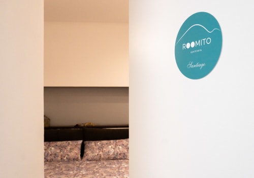 Ingresso della camera ROOMITO Apartments Santiago con insegna ovale teal, design minimalista moderno, Napoli