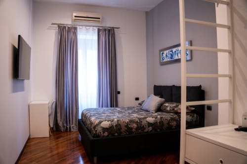 Leonardo Room at ROOMITO APARTMENTS Naples - modern bedroom with black bed, grey curtains, wooden floors, and city view
