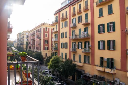 Colorful residential buildings in Naples with green shutters and balconies overlooking a courtyard from Roomito Apartments