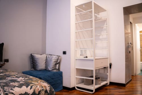 Modern bedroom at ROOMITO APARTMENTS Naples with bed, white shelving unit, and wood flooring