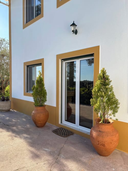 Entrada do pátio da Quinta Vale da Paz em Azambuja com portas em moldura ocre, vasos de cerâmica e arquitetura moderna