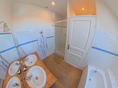 Modern bathroom in Chambre Bleue at Ferme De La Sensee B&B, featuring dual sinks, shower enclosure, and blue tile accents