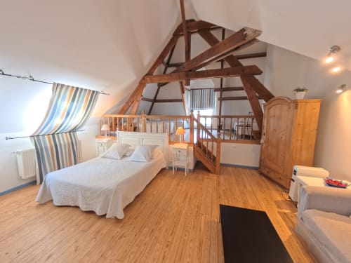 Suite Bleue bedroom at Ferme De La Sensee with exposed beams, queen bed, wooden loft and striped curtains
