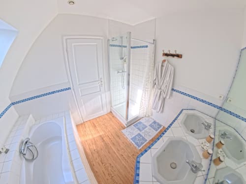 Modern bathroom in Suite Bleue at Ferme De La Sensee with shower, dual sinks, wood floors and blue tile accents