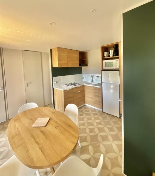 Cuisine-salle à manger moderne du mobil-home Domaine Pero Longo à Sartène, Corse, avec meubles en bois et mur d'accent vert