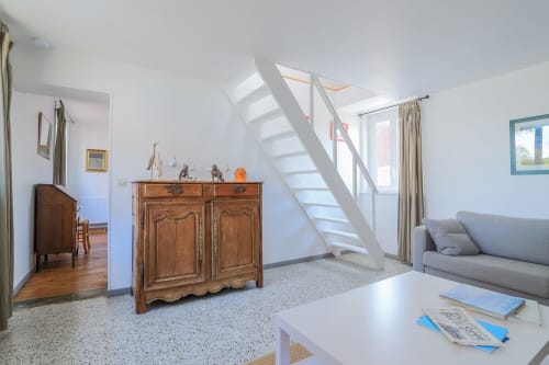 Séjour lumineux à la Maison Nolette avec mobilier en bois, escalier et vue sur le jardin en Baie de Somme