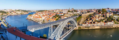 Aerial view of Porto's iconic Dom Luís Bridge spanning the blue Douro River with red-roofed buildings and historic cityscape
