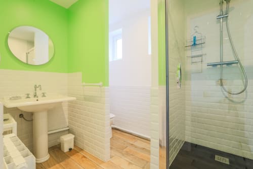 Salle de bains moderne et lumineuse du gîte Maison Nolette avec murs vert citron, lavabo sur pied, douche à l'italienne et plancher en bois