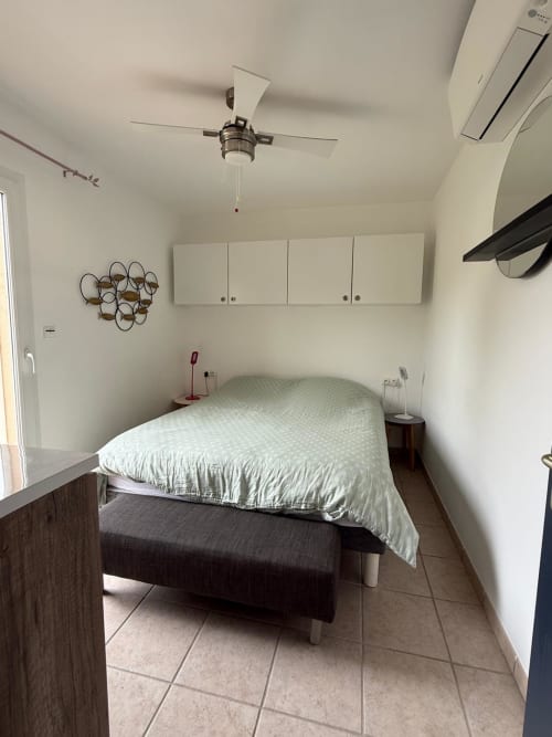Camera da letto moderna con letto queen size, ventilatore a soffitto, armadi bianchi e pavimentazione in piastrelle nella villa Conciergerie De Porticcio a Porticcio