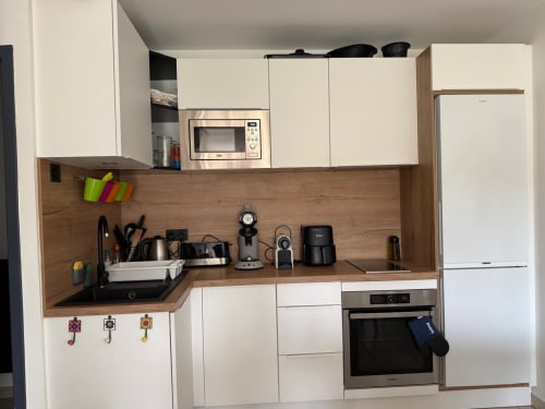 Cucina moderna nella villa della Conciergerie De Porticcio con mobili bianchi, piano in legno e elettrodomestici in acciaio inox