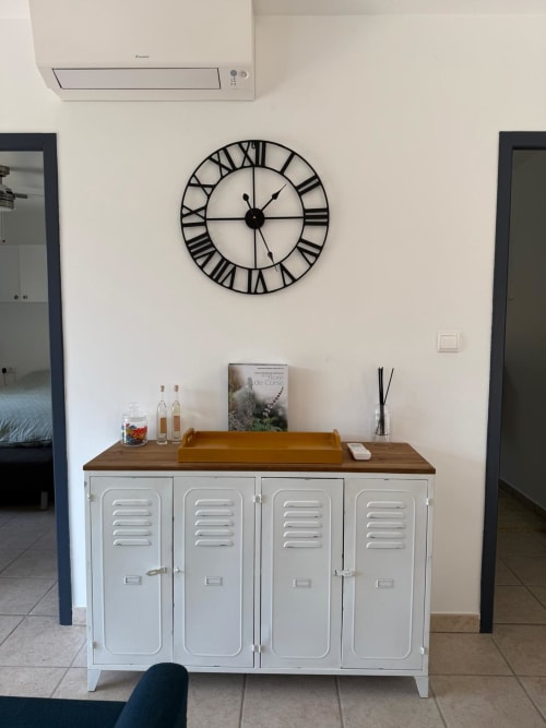 Ingresso di villa moderna con mobile metallico bianco per ripostiglio, piano in legno e orologio da parete con numeri romani
