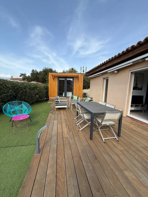 Ampio patio in giardino di villa a Porticcio con terrazza in legno, tavolo da pranzo, sedia turchese e vista sul rigoglioso giardino