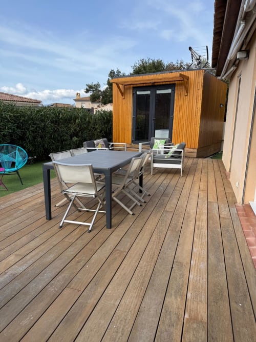Terrazza in legno con tavolo da pranzo, sedie e elegante chalet moderno alla villa Conciergerie De Porticcio a Porticcio