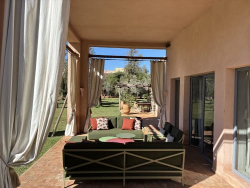 Terrasse couverte de Villa Elo Marrakech avec salon, rideaux fluides et vue sur le jardin