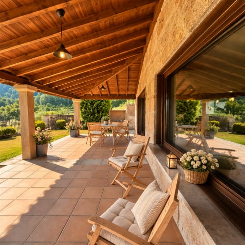 Terraza cubierta de Vila Lourido en Baiona con vigas de madera, comedor, tumbonas y vistas a la montaña